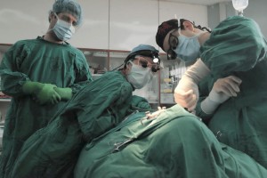 Doctors looking At Patient Under Medical Blankets On Operating Table