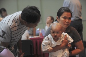 Thai Mom Holding Baby With Cleft Lip While Dad Leans In To Check On Baby